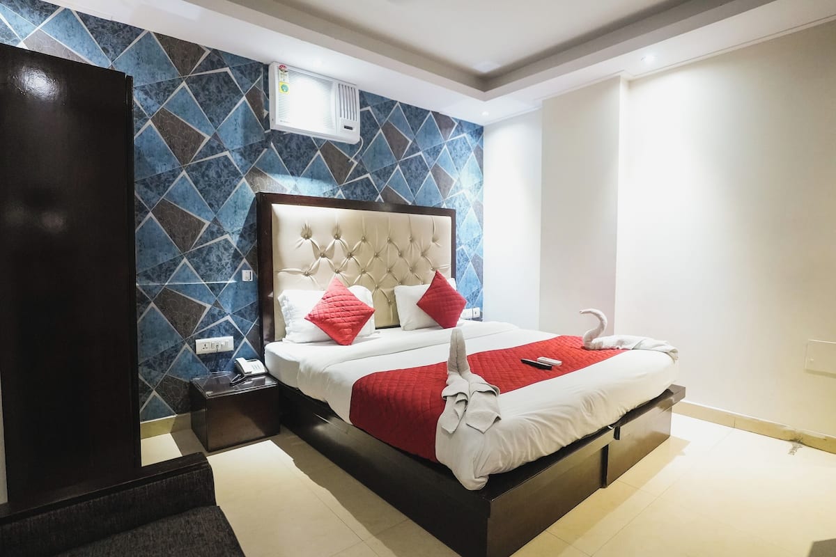 Una habitación de hotel moderna con una cama grande, un cabecero y una pared con estampado geométrico.