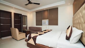A bedroom with a bed, a chair, a desk, a ceiling fan, and a window with blinds.