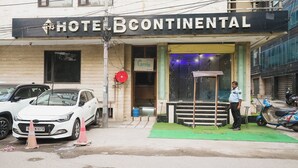 Un hotel chiamato 'Hotel Continental' con una insegna, un'auto bianca parcheggiata e una persona in piedi davanti.