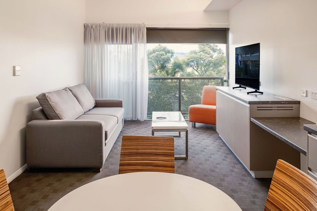A modern living room with a sofa, a dining table, and a TV.