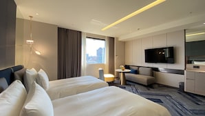 A hotel room with two beds, a sofa, a TV, and a city view. - Monarch Plaza Hotel (Taoyuan City)