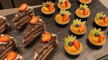 A variety of desserts arranged on a table, including chocolate cake slices and fruit-topped tarts.