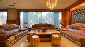 A luxurious living room with a large sofa set, a central coffee table, and a chandelier. - Monarch Plaza Hotel (Taoyuan City)