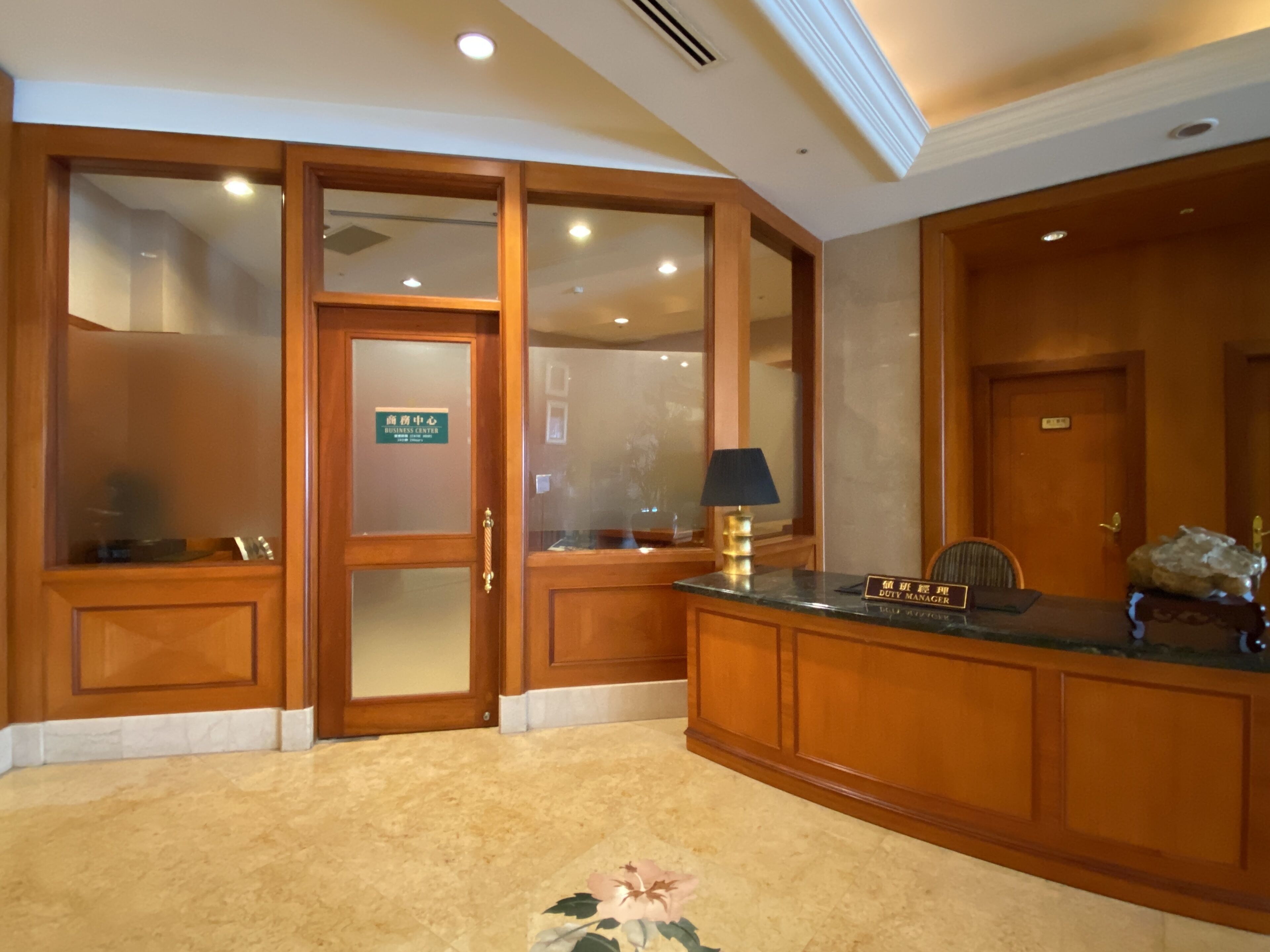 A reception area with a wooden desk, a nameplate, and a lamp.