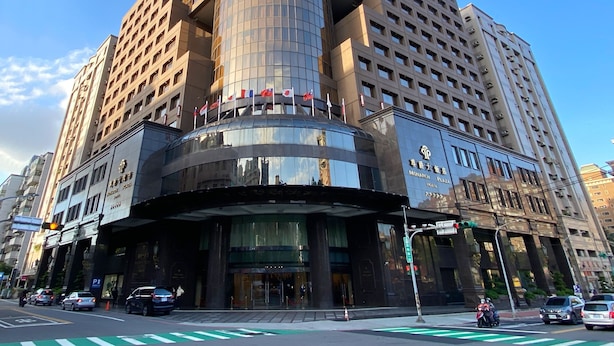 A modern hotel with a distinctive curved glass facade, multiple floors, and a prominent entrance with a canopy. - Monarch Plaza Hotel (Taoyuan City)