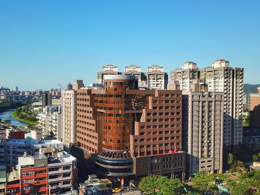 A high-rise building with a curved facade, surrounded by other tall buildings and a river in the background.
