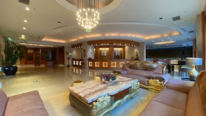 A spacious lobby with a reception desk, plush seating, a decorative coffee table, and a large chandelier. - Monarch Plaza Hotel (Taoyuan City)