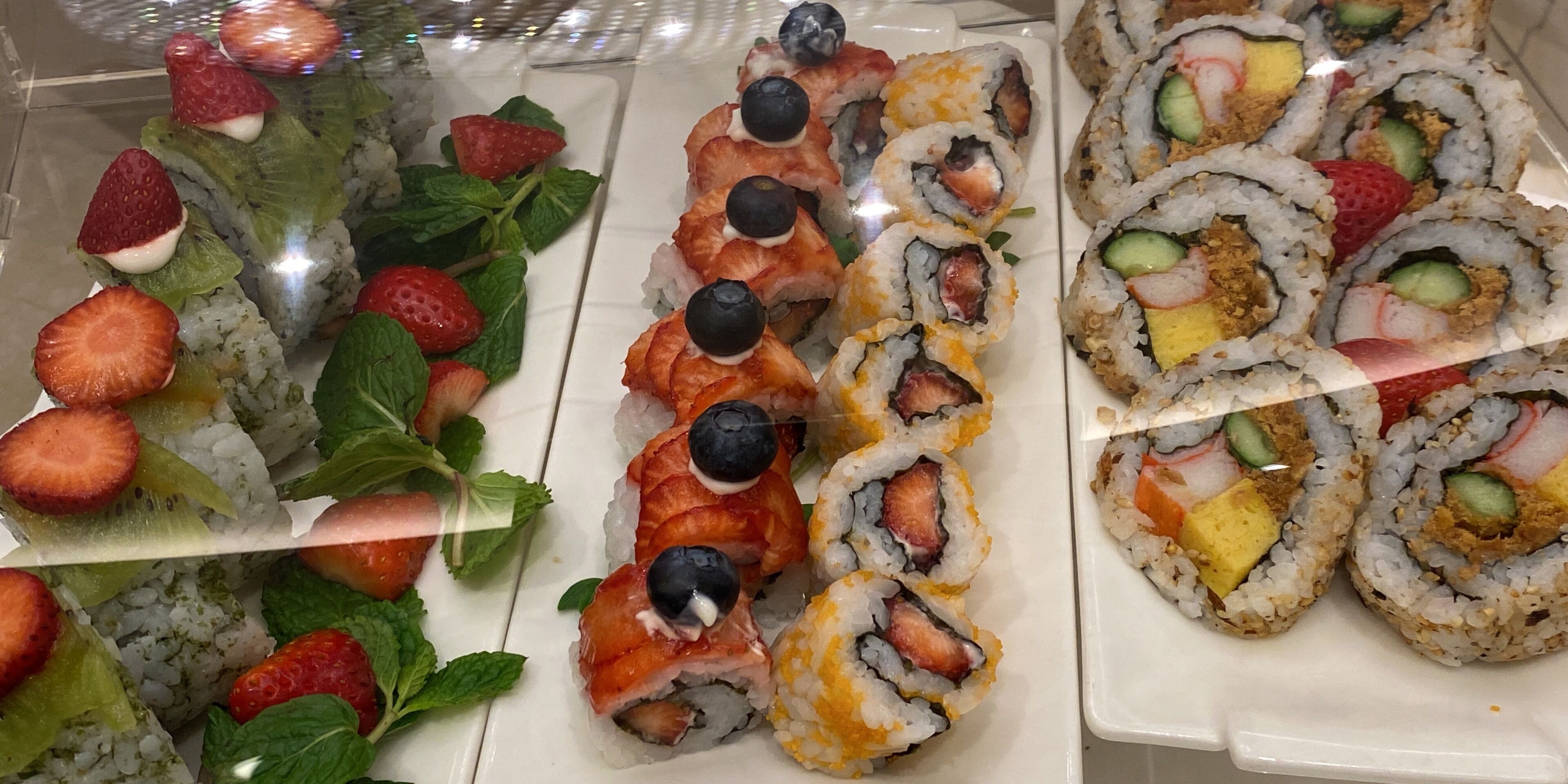 A variety of sushi rolls with different toppings, arranged on a white plate.