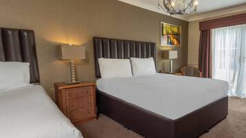 Una habitación de hotel con una cama grande, dos mesitas de noche, un candelabro y un cuadro en la pared.