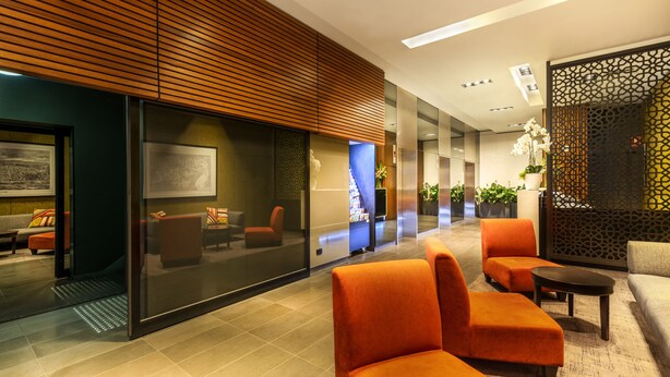 A modern lobby with orange seating, a reception area, and a decorative wooden panel. - Causeway 353 Hotel (Melbourne)