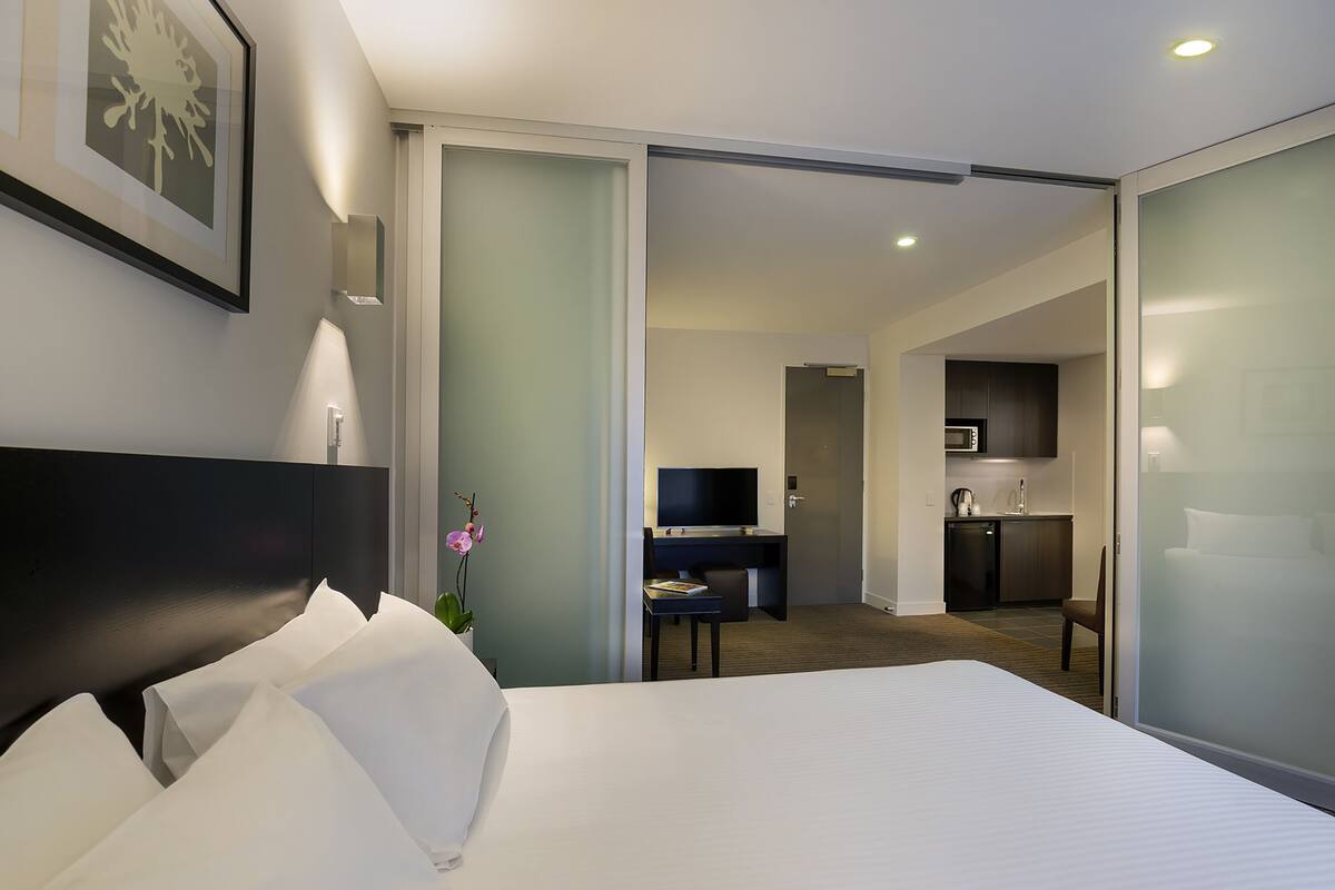 Une chambre d’hôtel équipée d’un lit, d’un bureau, d’une télévision et d’une kitchenette.