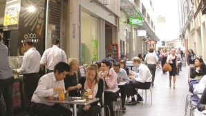 A busy outdoor café with tables and chairs, people sitting and eating, and a few standing. - Causeway 353 Hotel (Melbourne)