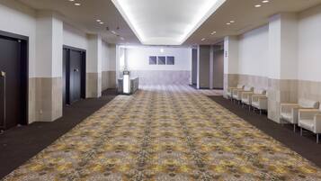 A hotel hallway with a patterned carpet, a reception desk, and seating area.