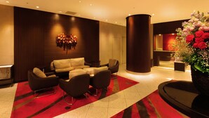 Eine moderne Lobby mit einer Sofagarnitur, einer großen Säule und einer Blumenkomposition.