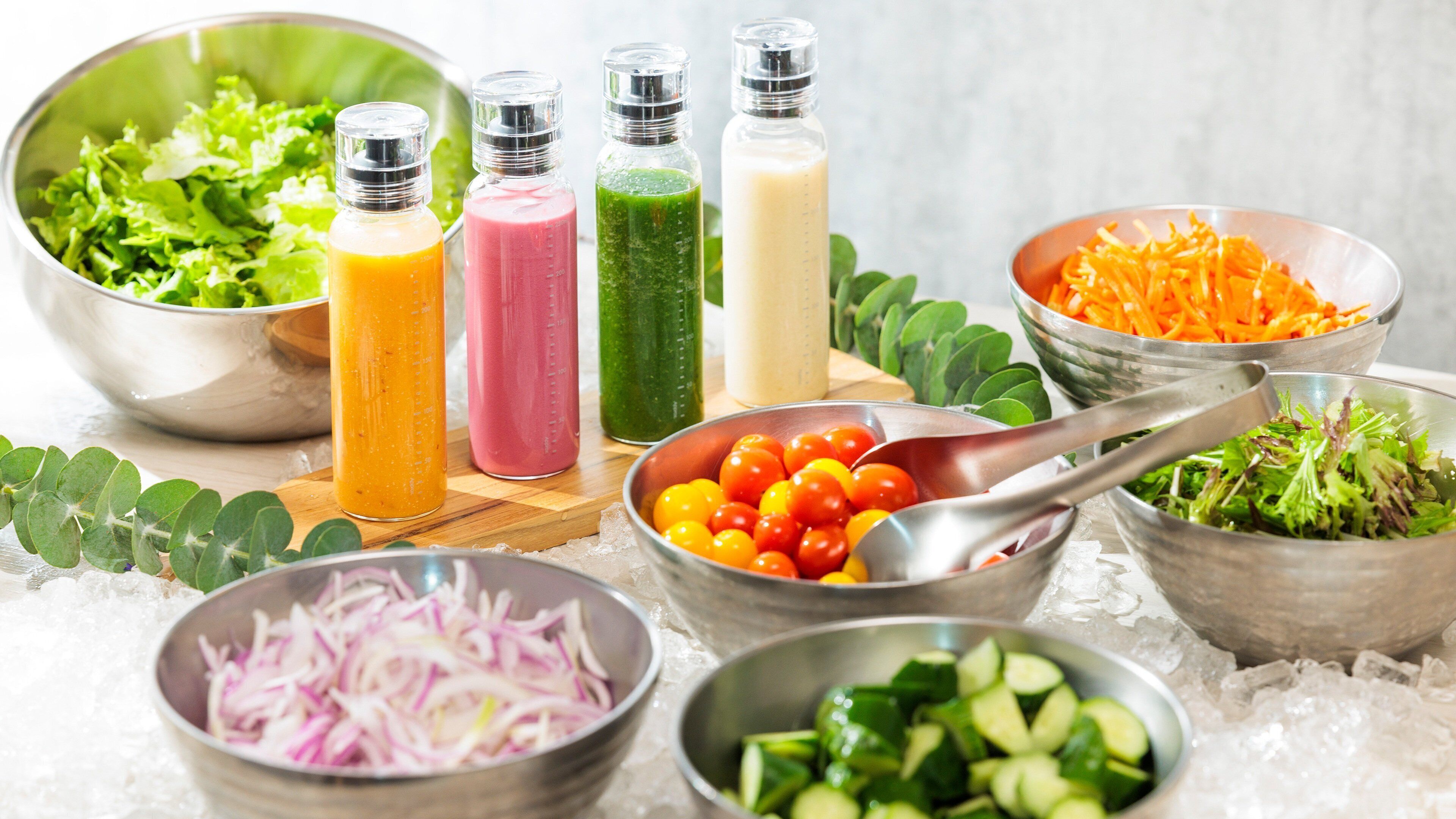 A variety of fresh vegetables and salad dressings on a table.