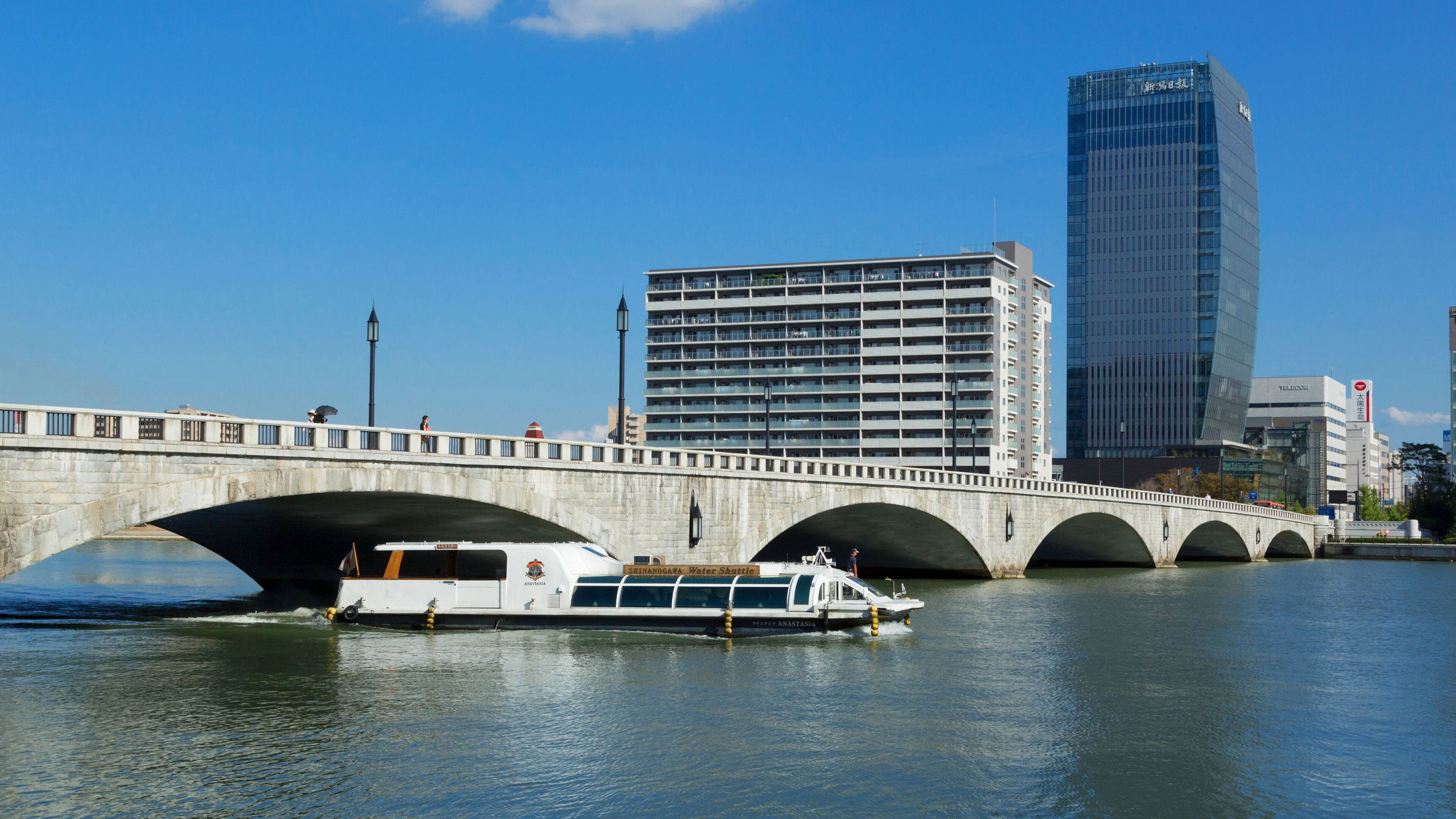A bridge with a water shuttle boat passing underneath.