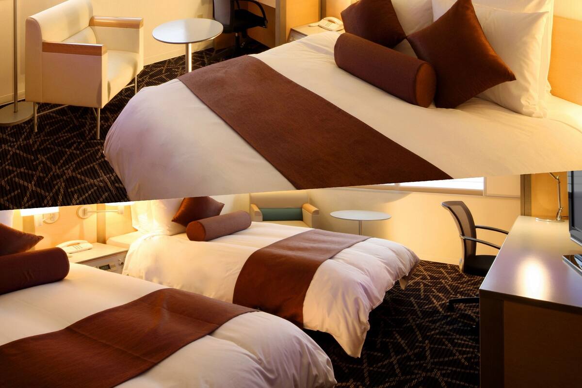 Ein Hotelzimmer mit einem großen Bett, einem Schreibtisch, einem Sessel, einem kleinen Tisch und einem Fernseher.