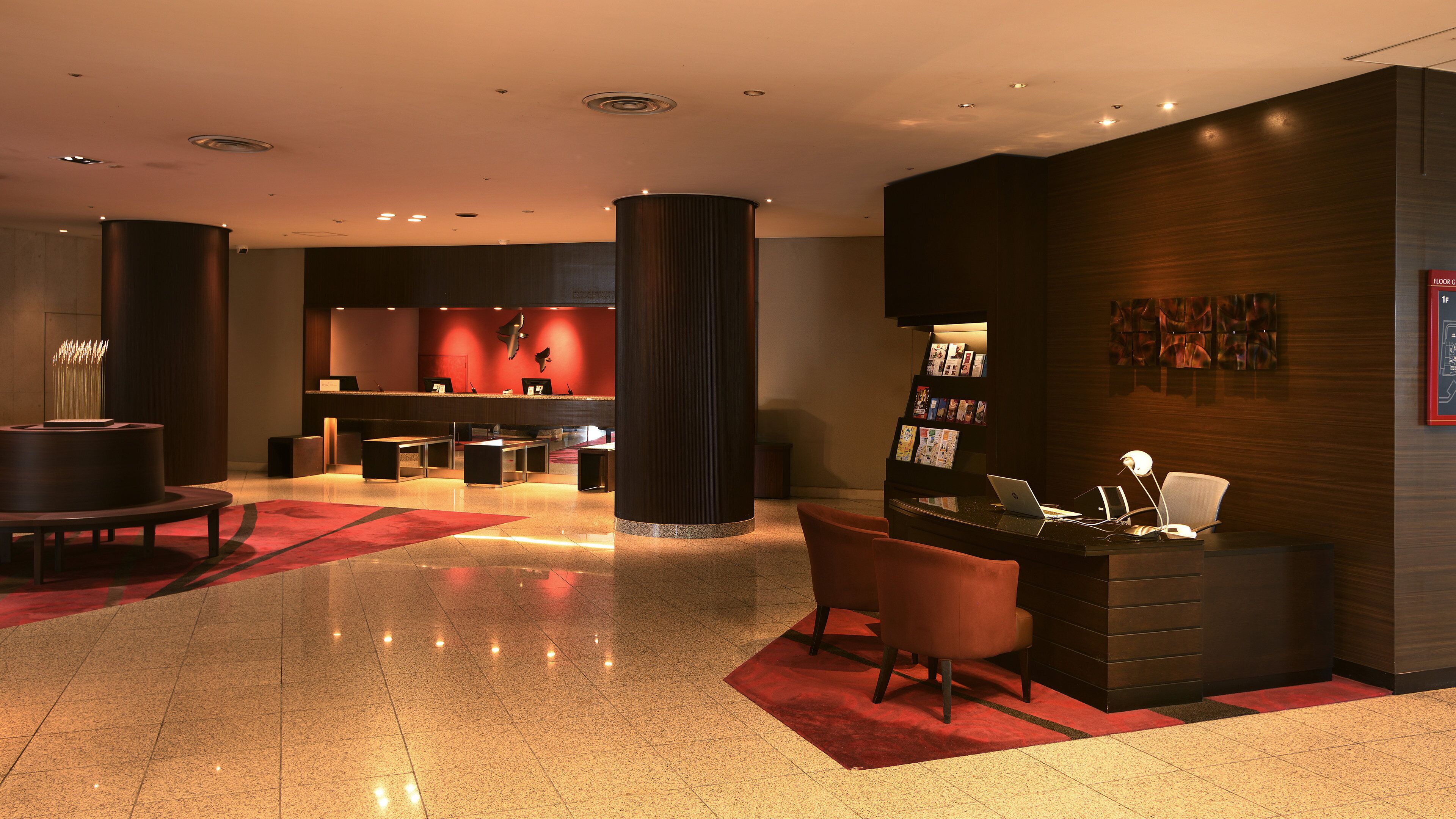 A modern lobby with a reception desk, seating area, and a large pillar.