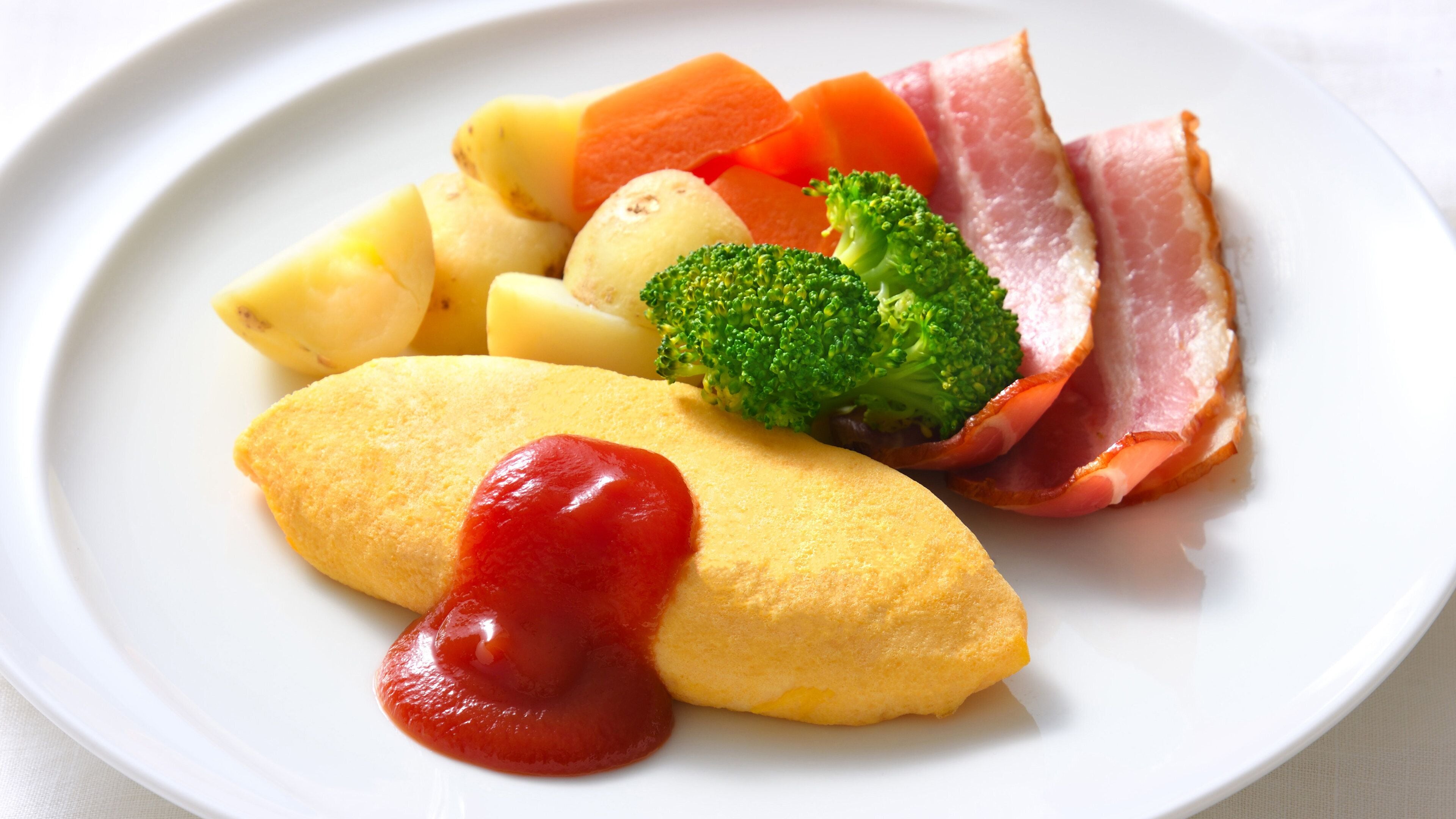 A plate with ham, potatoes, carrots, broccoli, and a slice of egg.