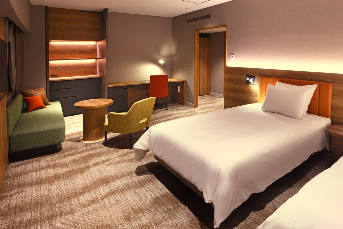 Ein Hotelzimmer mit einem großen Bett, einer Sitzecke, einem Schreibtisch und einem Sessel.