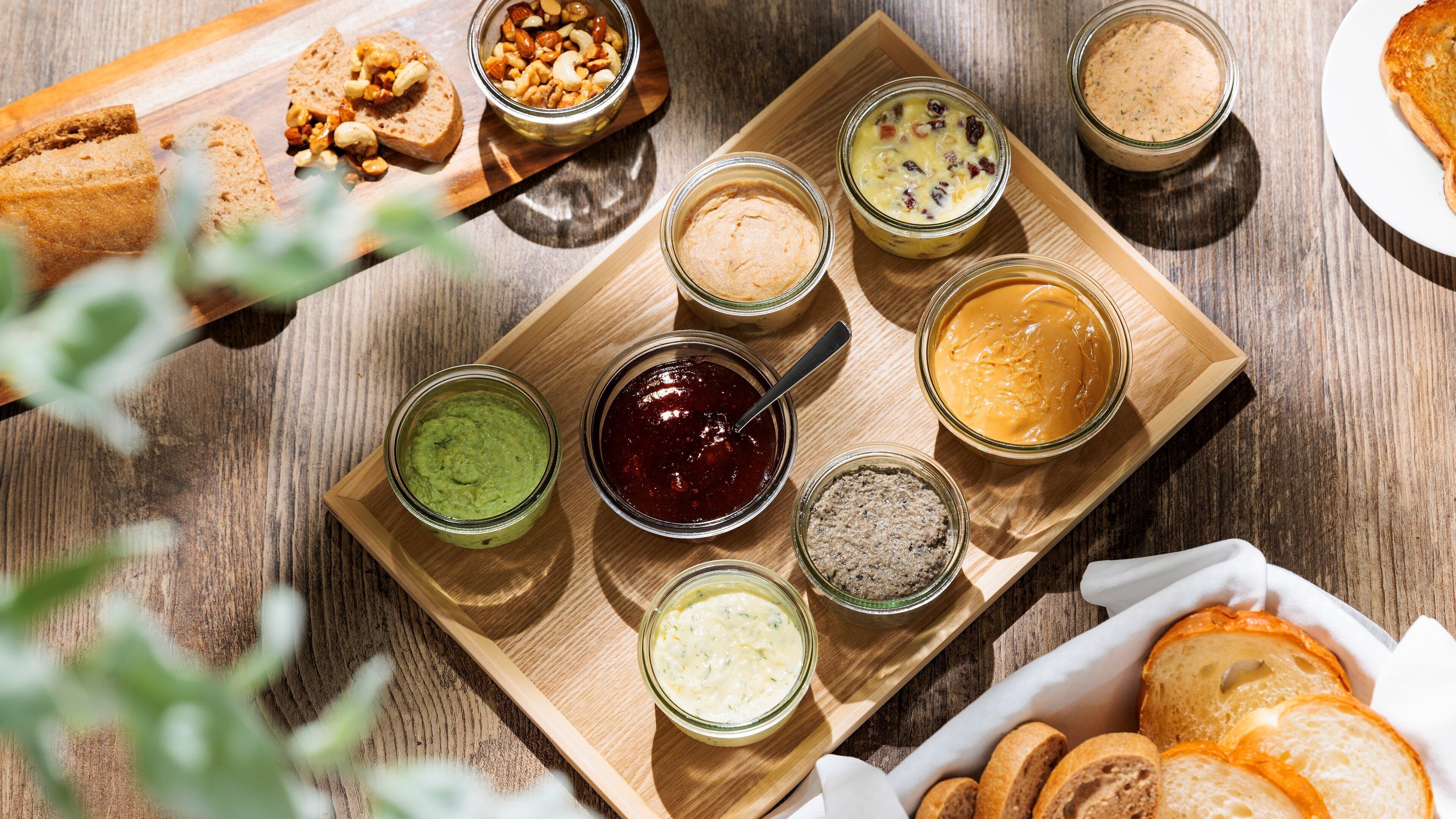 A wooden tray with various food items and bread slices.