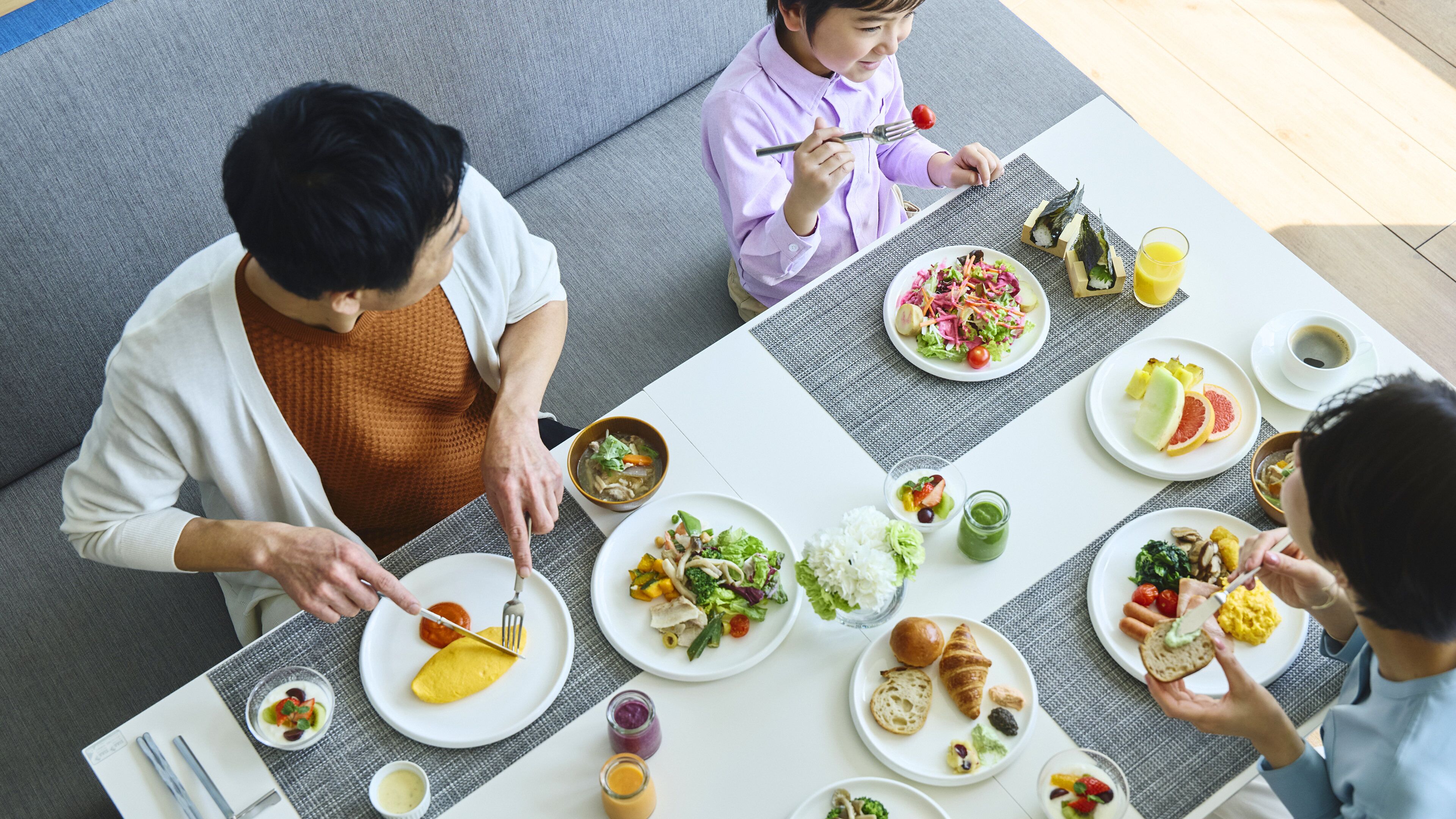 A dining table with various dishes, including salads, rice, and a croissant.