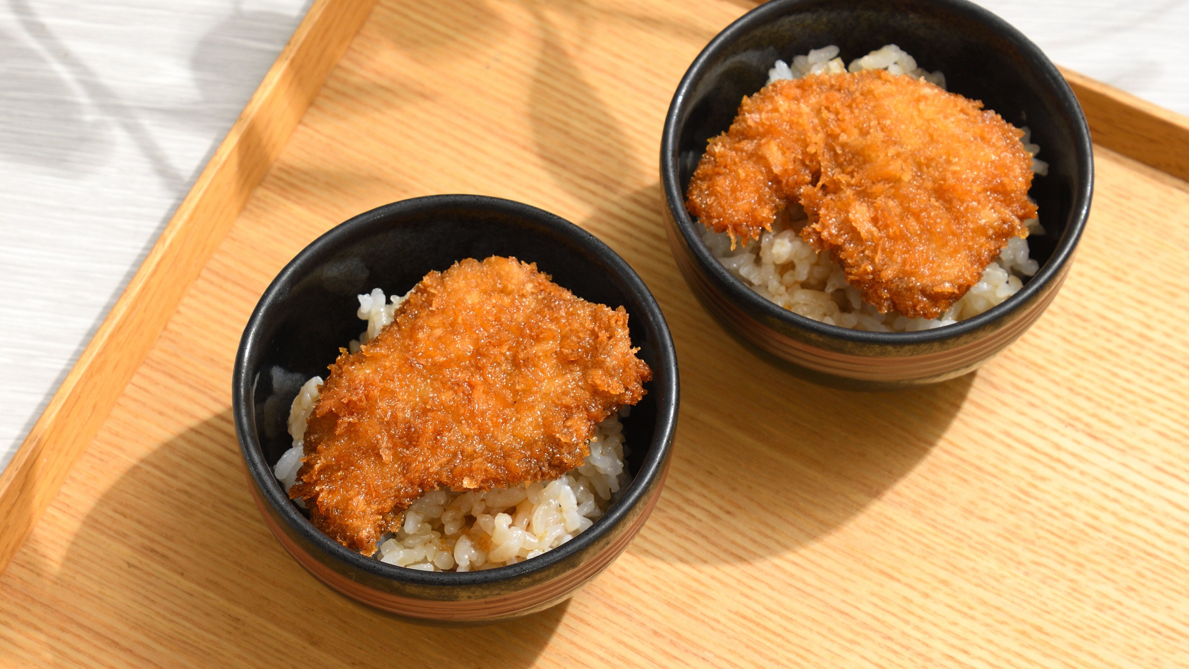 Deux bols de riz accompagnés de poisson frit, servis sur un plateau en bois.