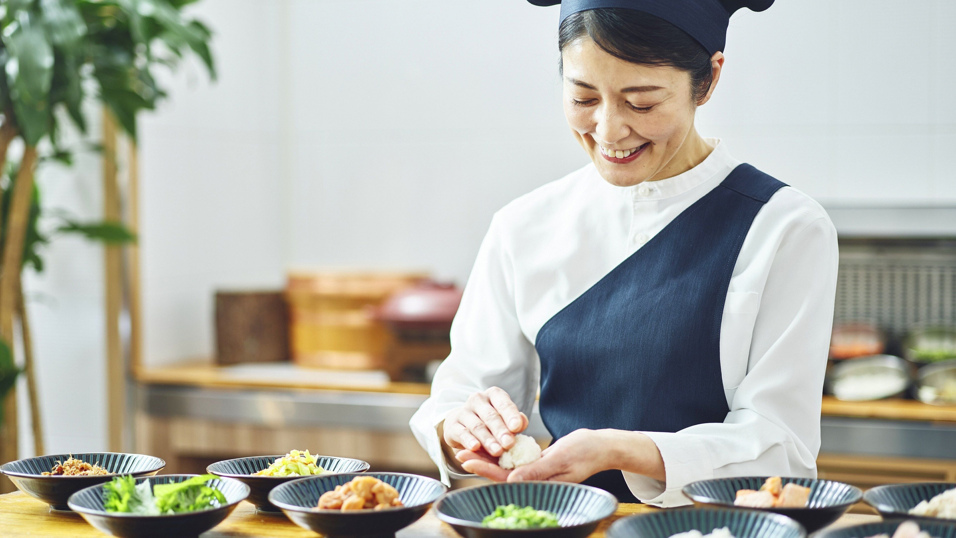 A person serving food in a restaurant with multiple dishes on the table.