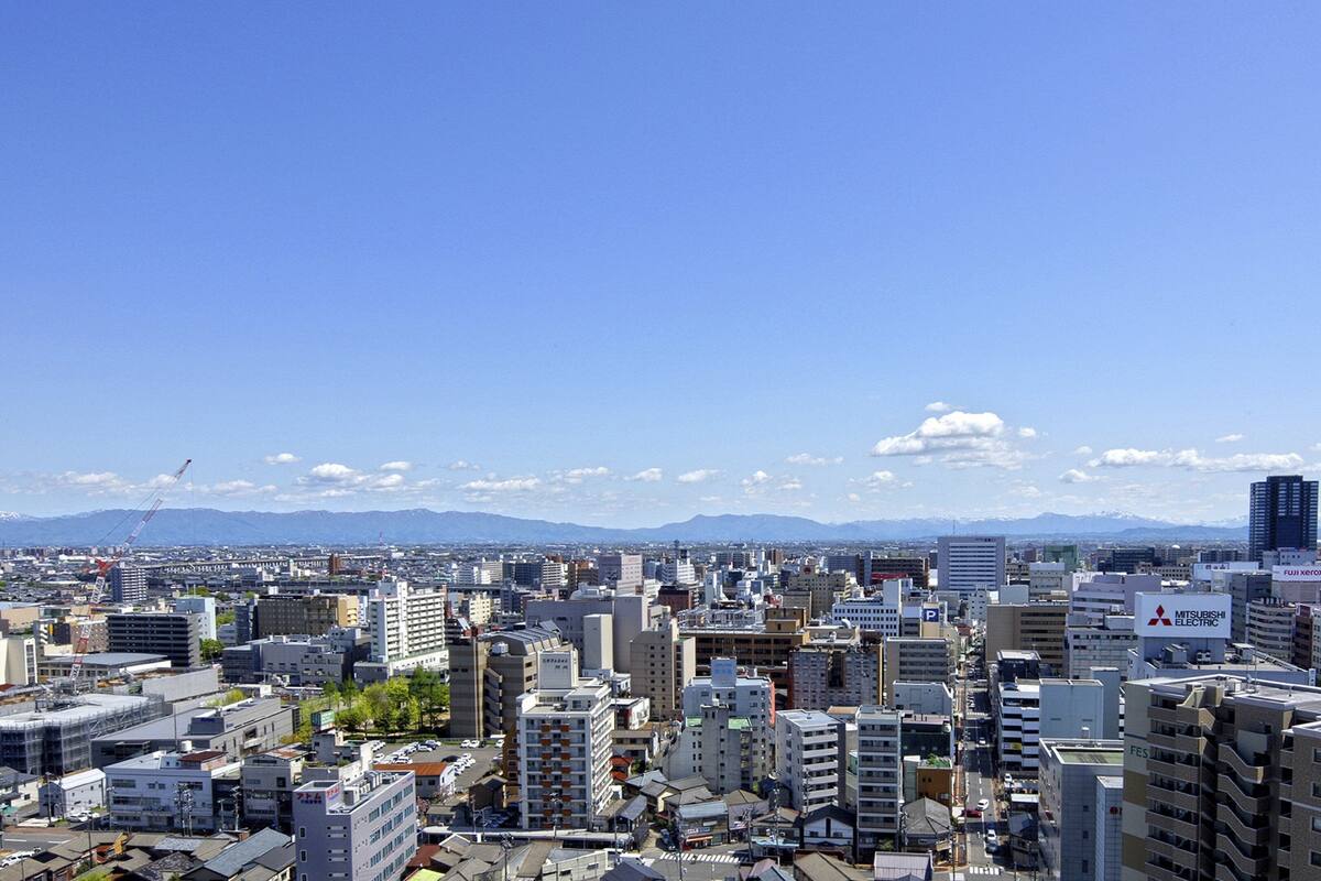 Paisagem urbana com diversos edifícios, incluindo uma placa da Mitsubishi Electric em destaque.