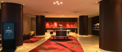 A hotel lobby with a reception desk, a seating area, and a large pillar.
