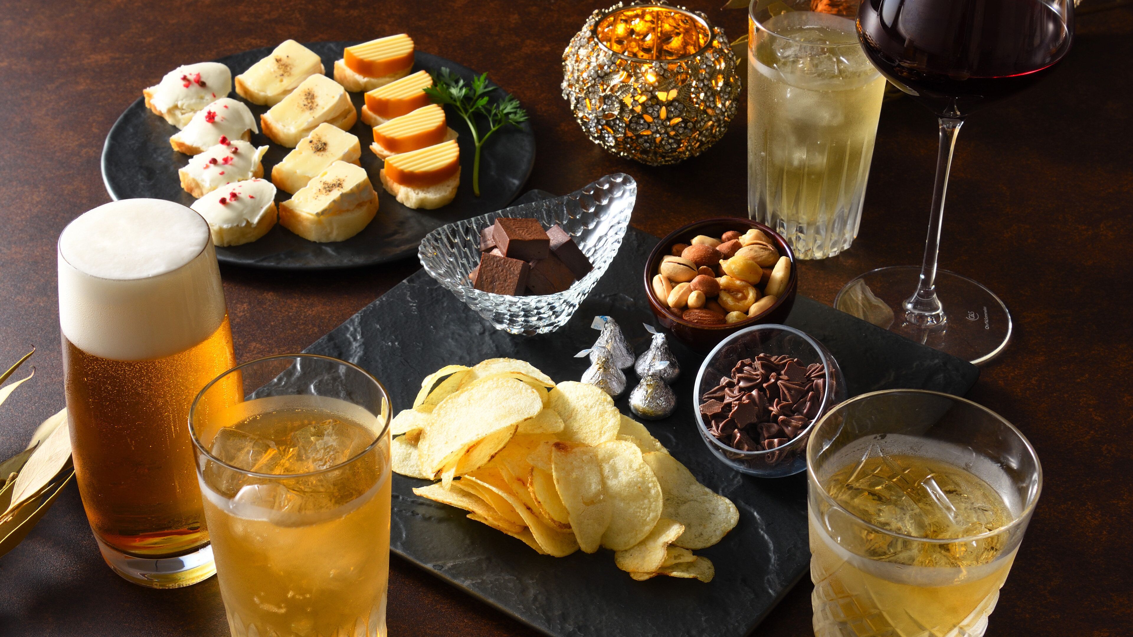 A table set with various snacks, drinks, and a decorative candle.