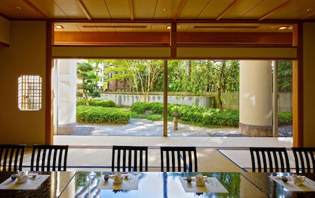 A conference room with a view of a landscaped garden through large windows.