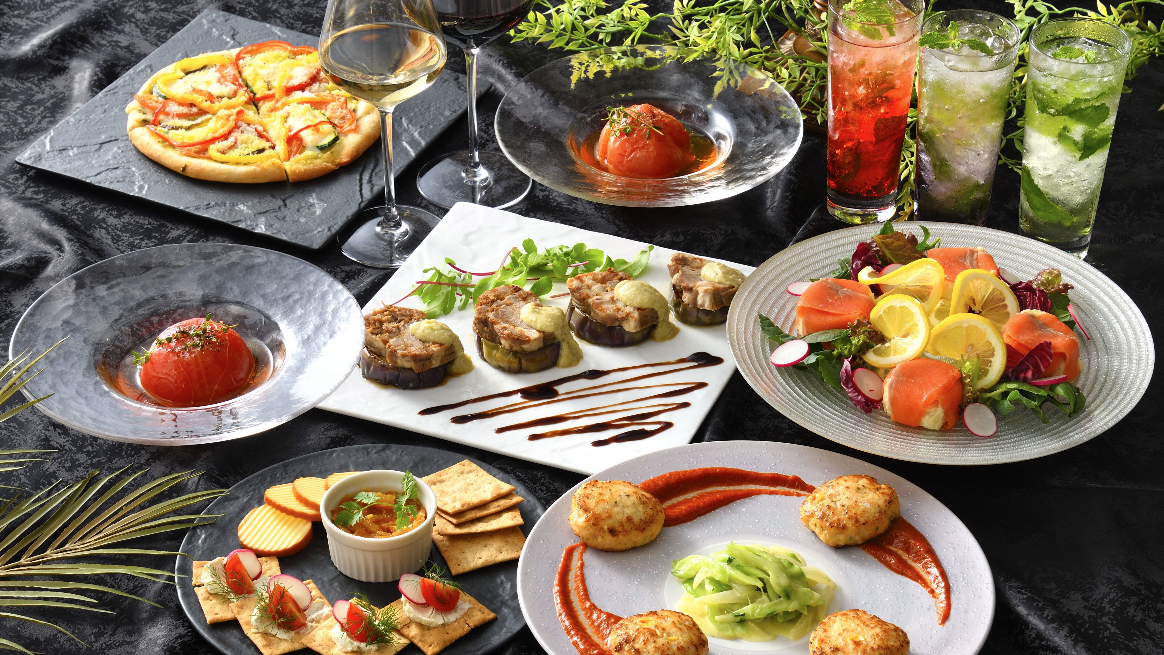 A variety of dishes including pizza, a tomato-based dish, and a salad with salmon and vegetables.