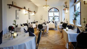 Un restaurante con varias mesas, sillas y un suelo de madera en espiga.