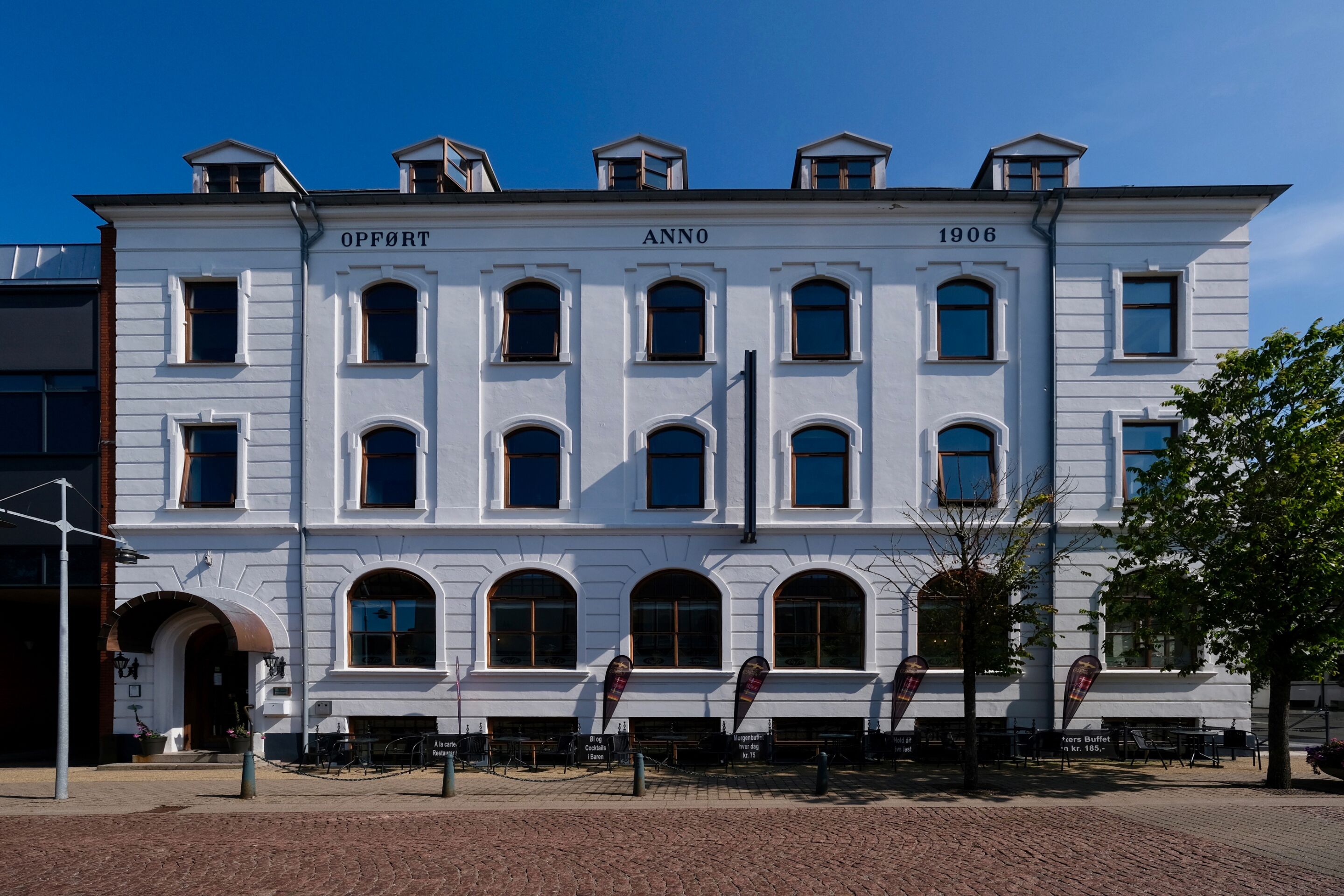 A white building with the name "OPFÖRT" and the year "1906" on the facade.