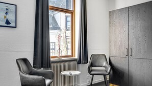 Een kamer met twee leren fauteuils, een kleine ronde tafel, een radiator en een grote kast.