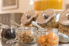 A breakfast bar with various food items in glass containers, including granola, dried fruits, and nuts. - Heartland Hotel Glacier Country (Fox Glacier)