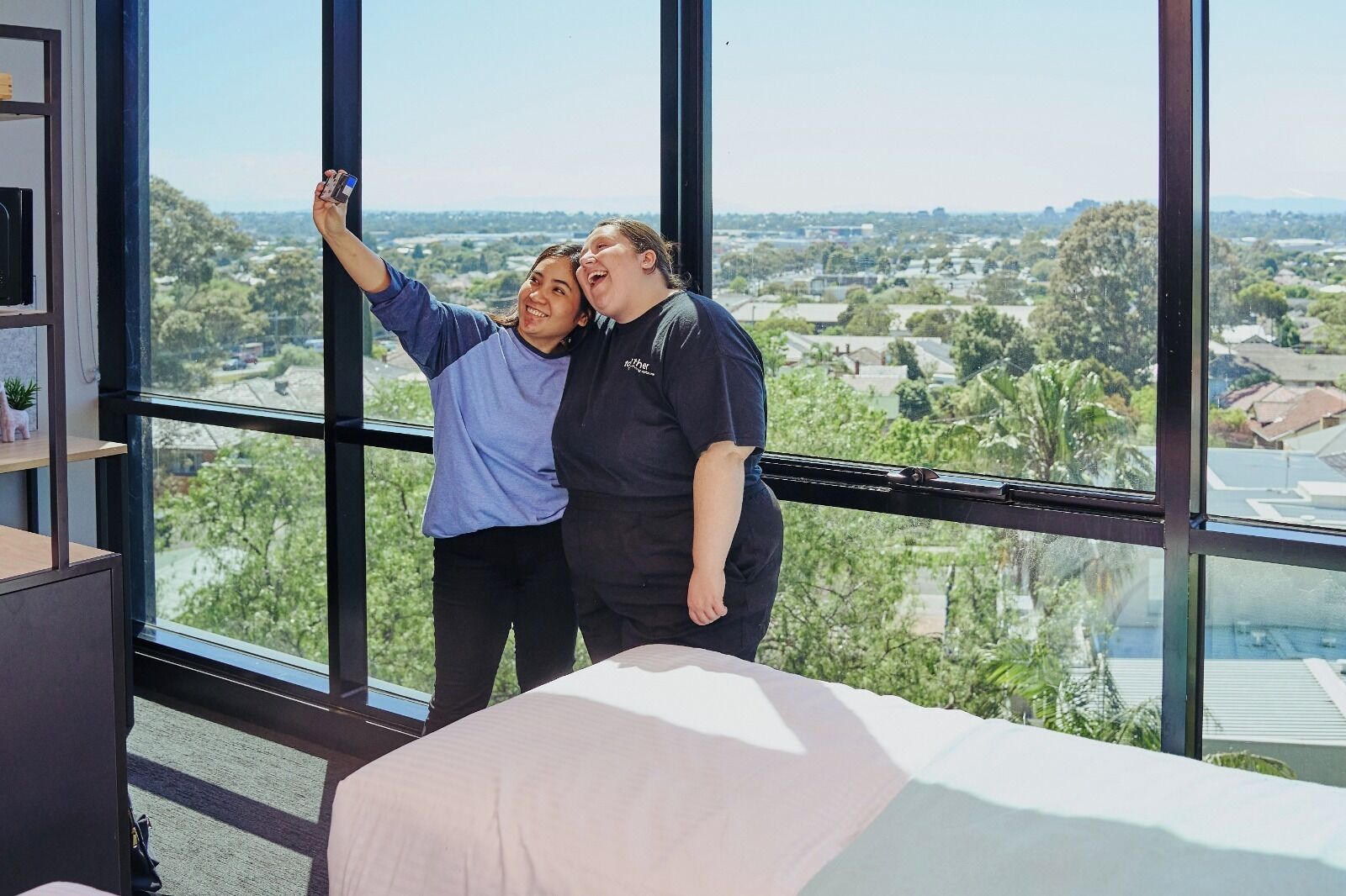 A room with large windows offering a view of a cityscape.