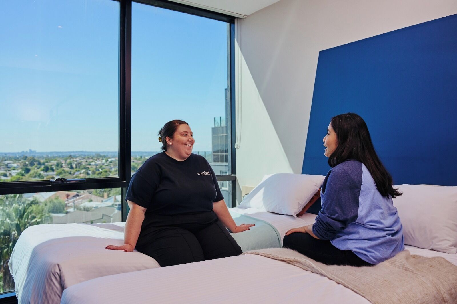 A modern room with large windows, a bed, and a blue accent wall.