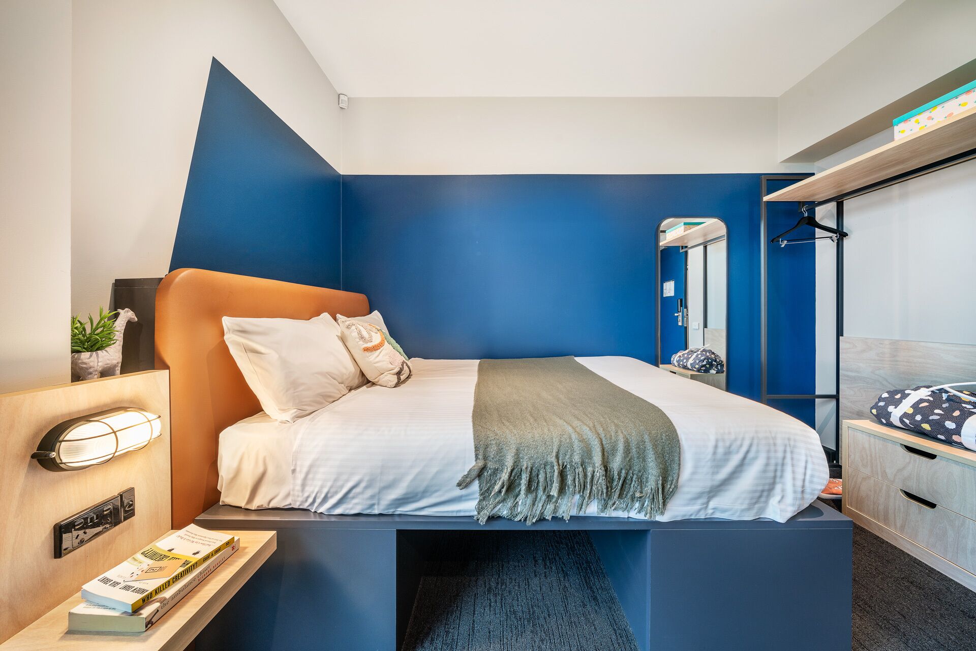 A modern bedroom with a bed, bedside table, and a wardrobe.