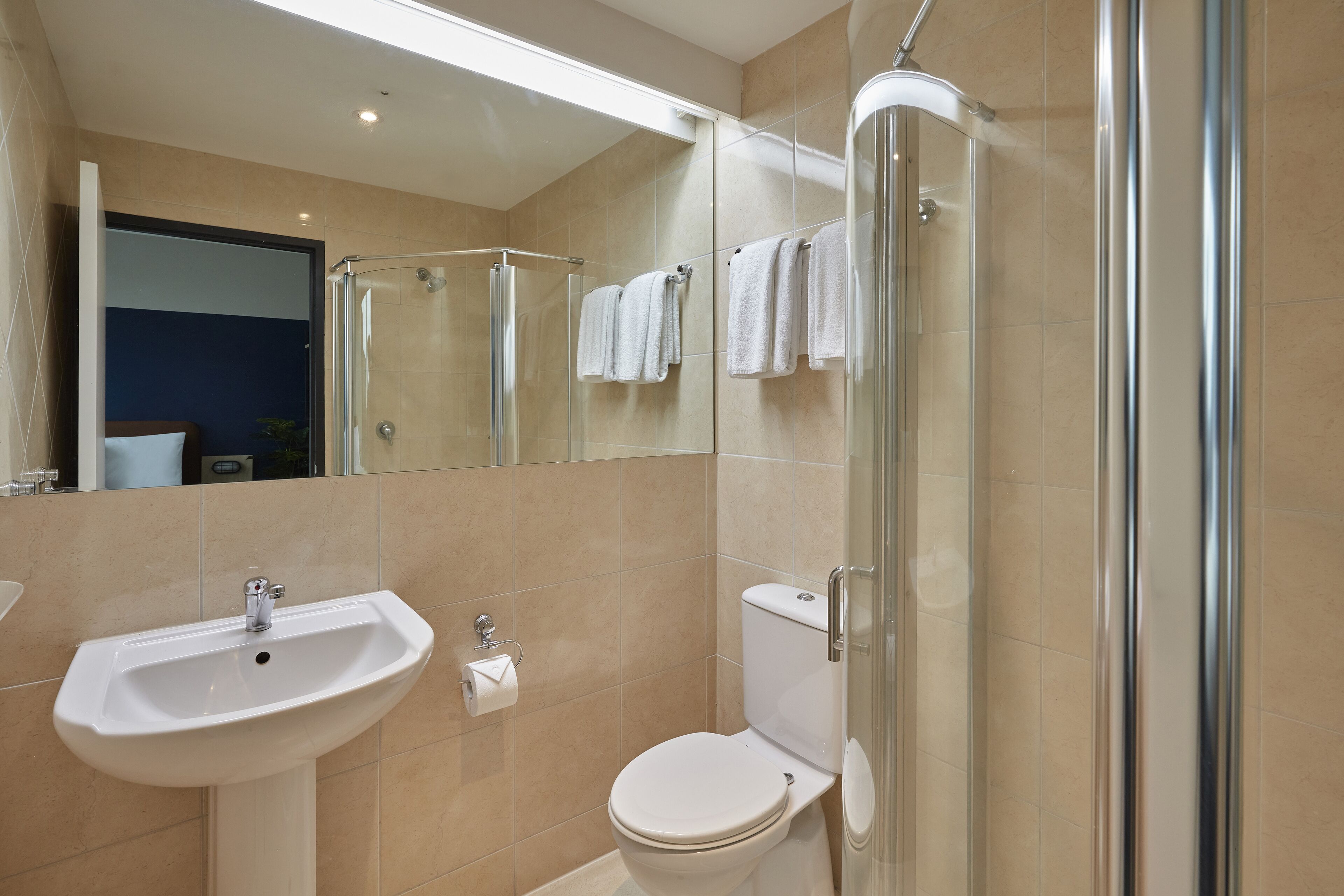 Un baño moderno con cabina de ducha de vidrio, un lavabo blanco y un inodoro.