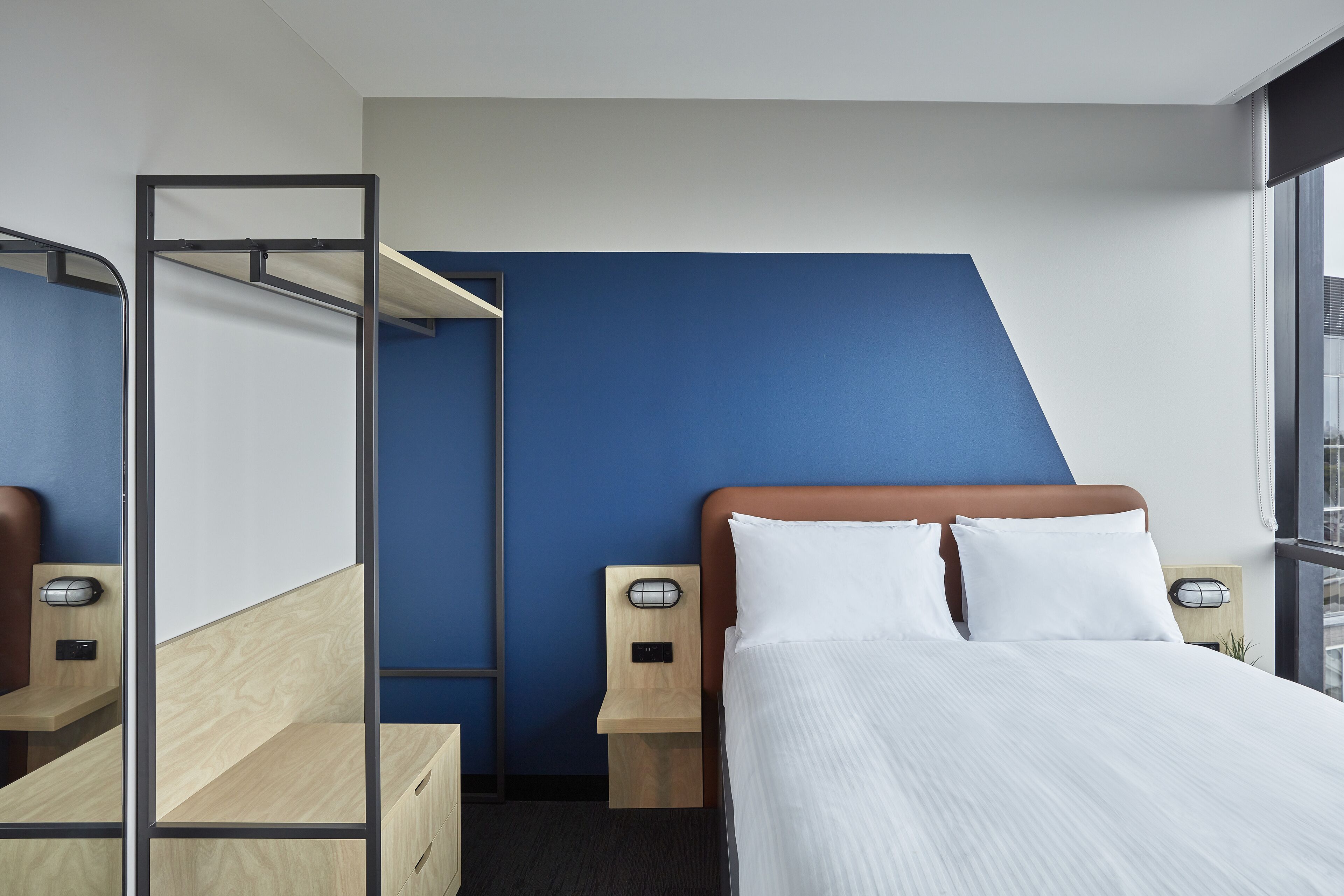 Una habitación de hotel moderna con cama, escritorio y armario.