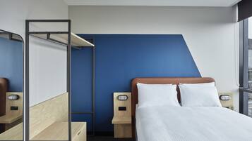 A modern hotel room with a bed, a desk, and a wardrobe.