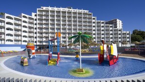 Un parc aquatique doté de diverses structures de jeux et d’un grand bâtiment en arrière-plan.