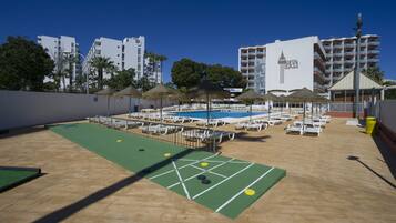 A pool area with lounge chairs and a shuffleboard court.