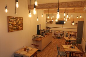 A restaurant with wooden tables and chairs, hanging light bulbs, and a kitchen area. - Scarborough Travel and Holiday Lodge (Scarborough)