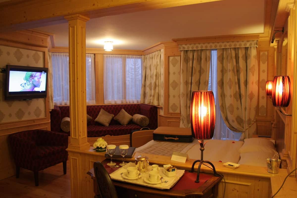 Un accogliente soggiorno con un divano rosso, un tavolino in legno con un set da tè, una televisione e una lampada.