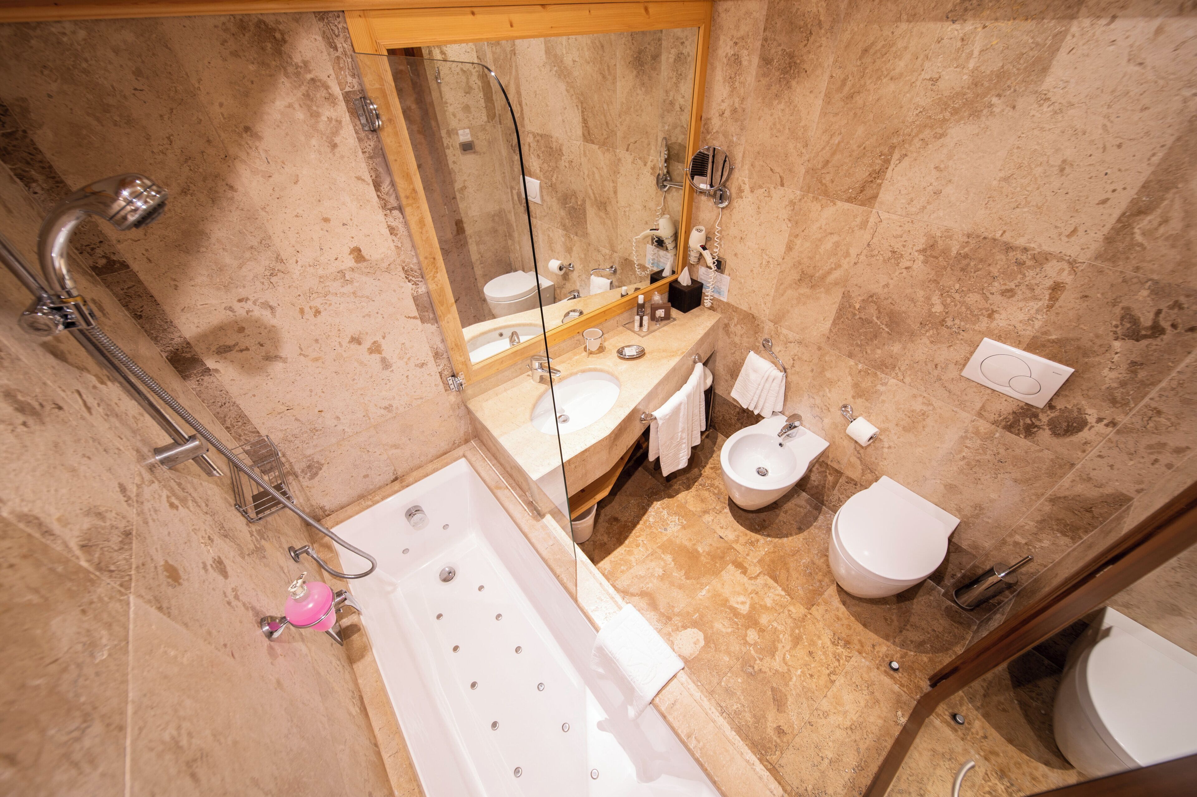 Et badeværelse med badekar, håndvask, toilet og bidet.