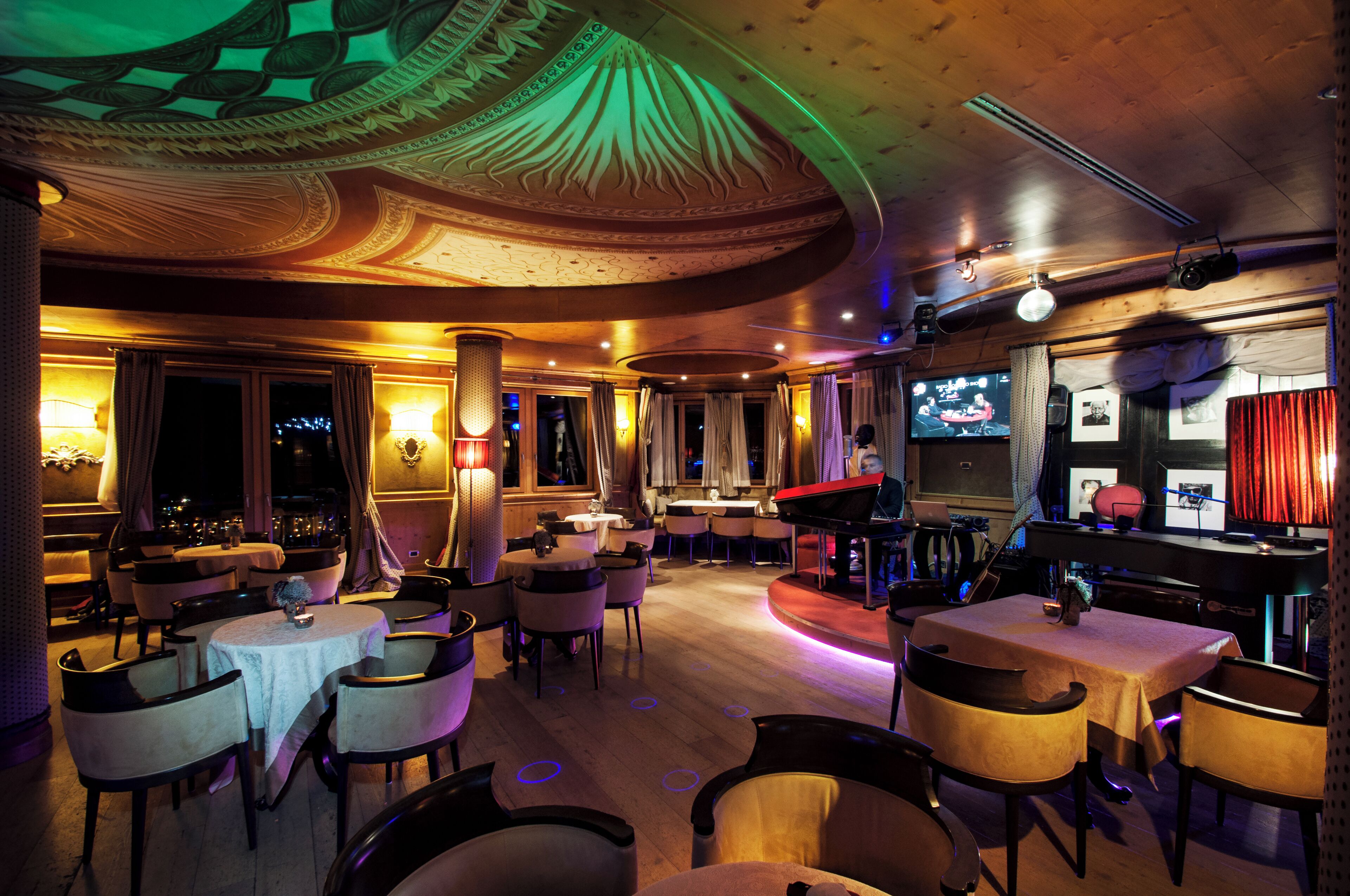 Un ristorante con tavoli e sedie rotonde, un'area bar e uno schermo televisivo.