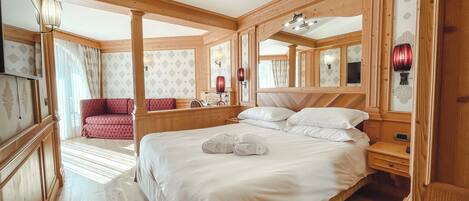 A spacious bedroom with a large bed, wooden headboard, and a red sofa in the corner.